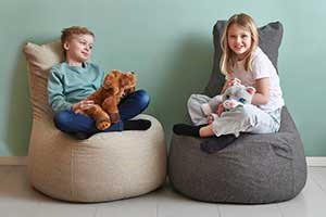 Gutt og jente sitter i hver sin saccosekk med taktile kosedyr