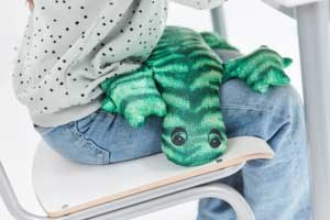 Barn som sitter på stol med vektpute i fanget